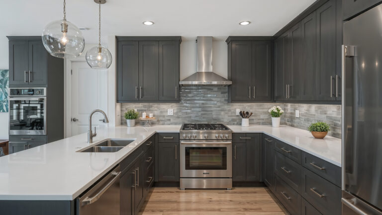 Elegant gray kitchen featuring stainless steel appliances, quartz countertops, and stylish glass pendant lights, creating a sophisticated culinary space. Ai generated image